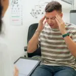 man with headache talking to doctor