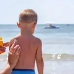 mom putting sunscreen on young son