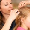 woman looking for lice on a child's head