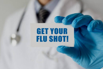 doctor holding sign that says get your flu shot