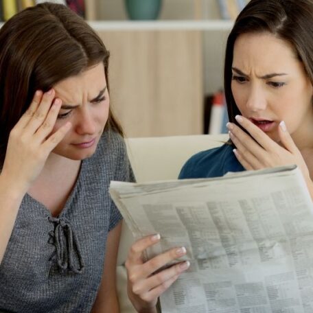 2 concerned women reading the paper