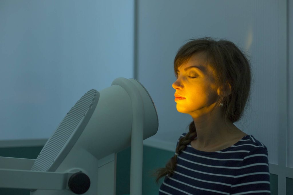 Woman, eyes closed, facing a light box