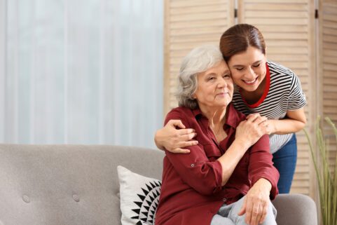 Elderly woman hugged by younger caregiver