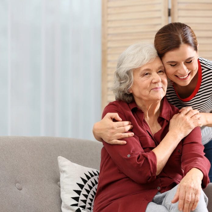 Elderly woman hugged by younger caregiver