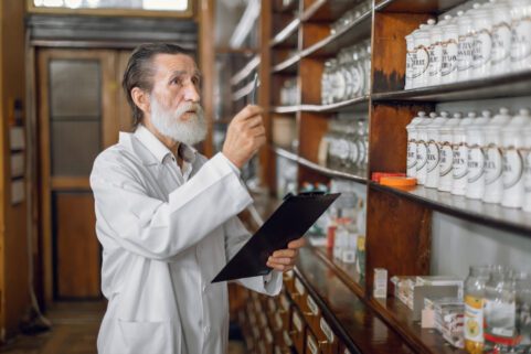 pharmacist looking at drugs on shelf