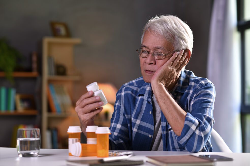 medication safety for older adults, older man looking at pill bottles