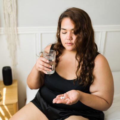 Migraine Drugs and High Blood Pressure, Circulation Problems , woman about to take tablet