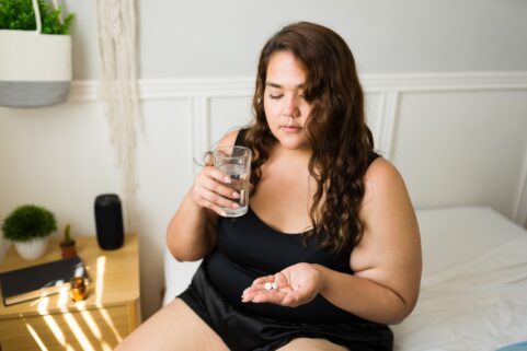 Migraine Drugs and High Blood Pressure, Circulation Problems , woman about to take tablet
