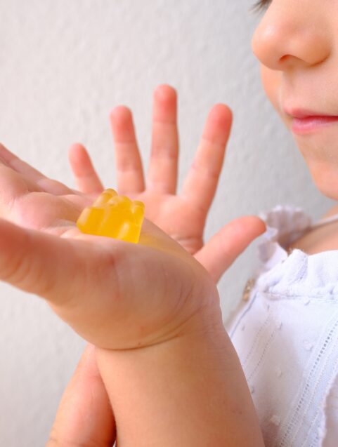 small child holding melatonin gummy