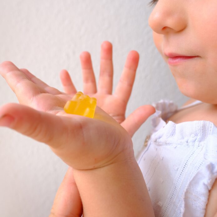 small child holding melatonin gummy