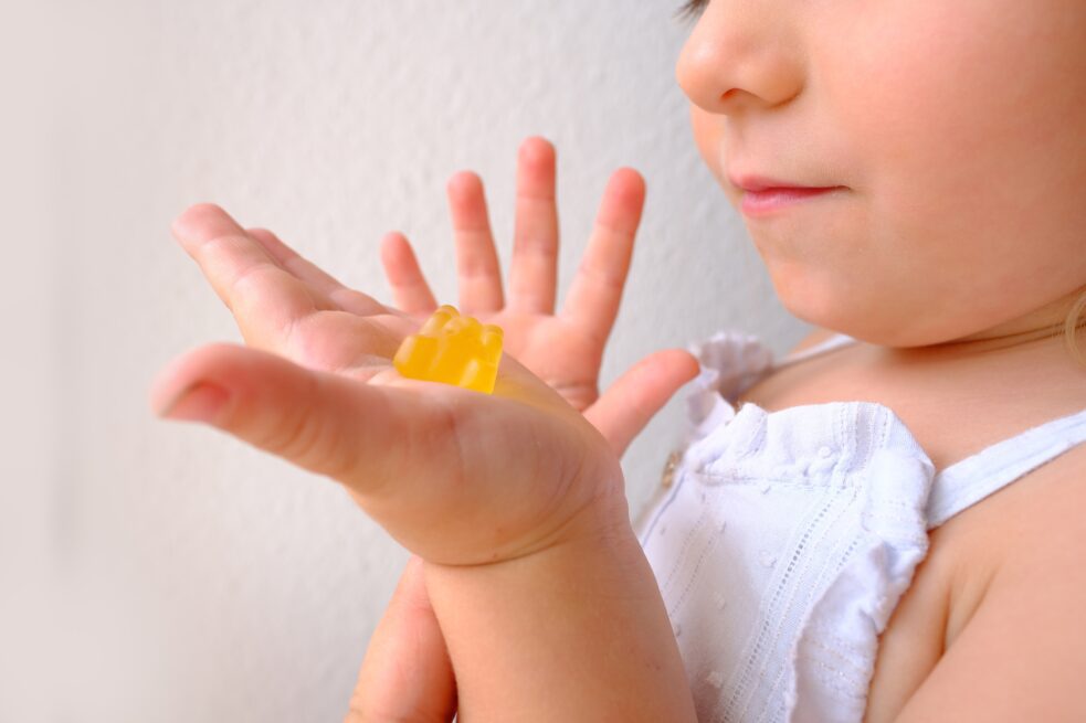small child holding melatonin gummy