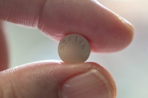 statins, side effects and cholesterol, fingers holding stain pill