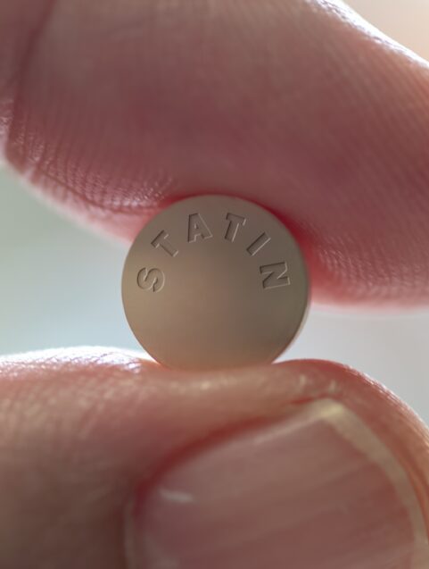 statins, side effects and cholesterol, fingers holding stain pill