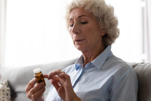drug recalls and warnings, woman looking at pill bottle