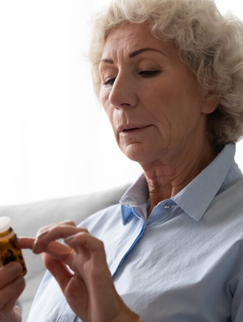 drug recalls and warnings, woman looking at pill bottle