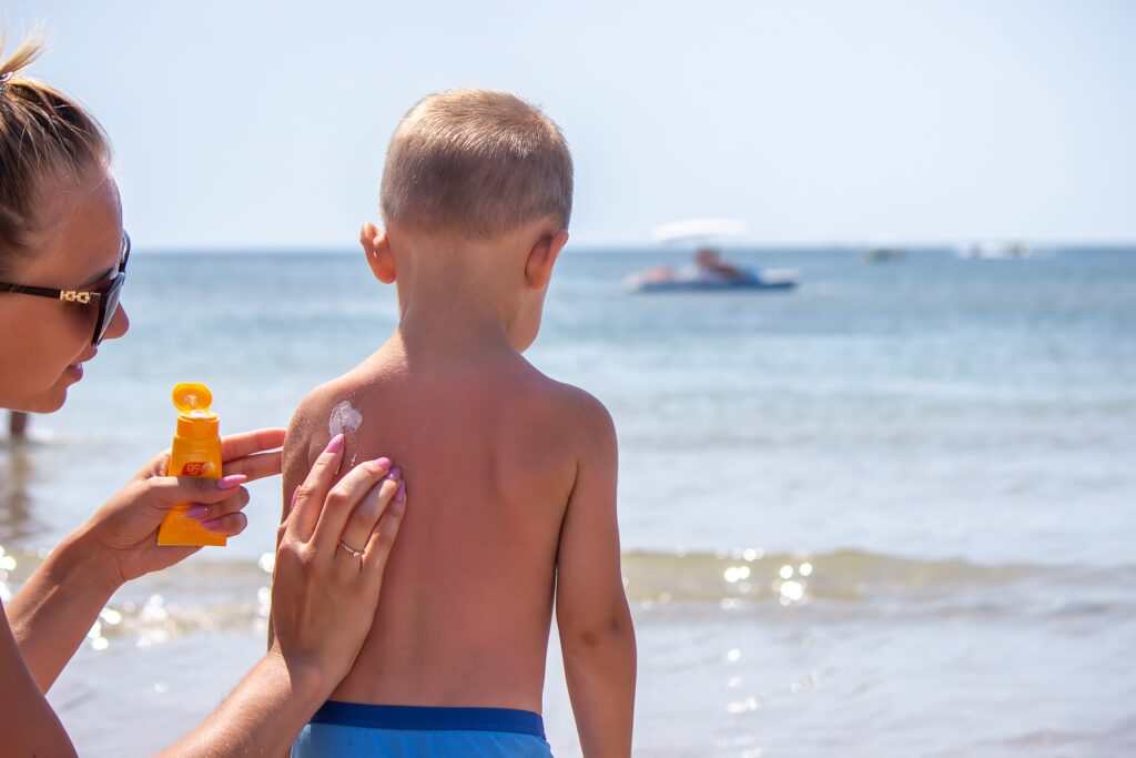 mom putting sunscreen on young son