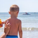 mom putting sunscreen on young son