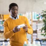 man checking out cream in drug store